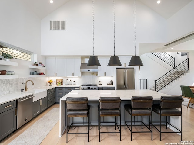 kitchen featuring pendant lighting, sink, white cabinetry, stainless steel appliances, and a kitchen breakfast bar