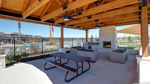 view of patio featuring ceiling fan and an outdoor living space with a fireplace