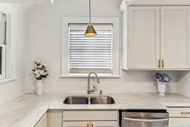 kitchen with pendant lighting, dishwasher, sink, white cabinets, and light stone countertops