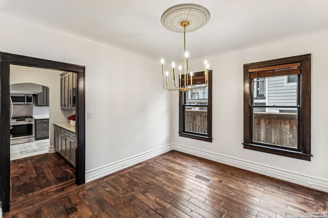 unfurnished dining area with a chandelier and dark hardwood / wood-style flooring