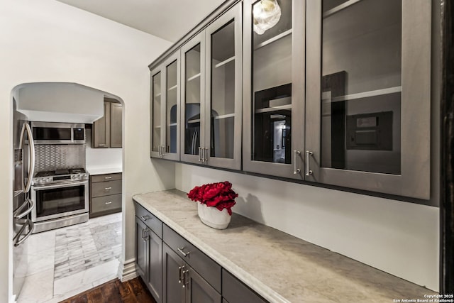 kitchen with appliances with stainless steel finishes, light stone countertops, and backsplash