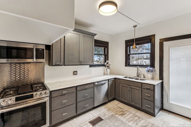 kitchen featuring appliances with stainless steel finishes, pendant lighting, sink, backsplash, and dark brown cabinets