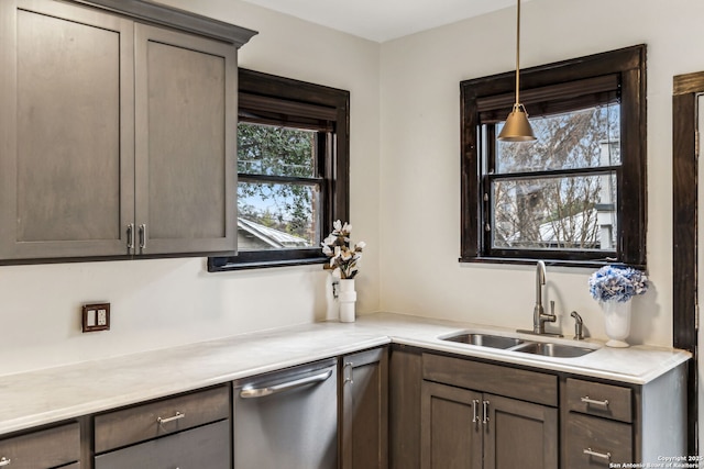 kitchen featuring stainless steel dishwasher, dark brown cabinetry, sink, and hanging light fixtures