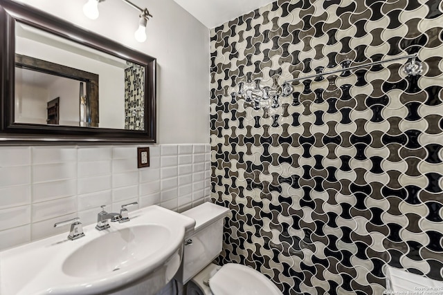 bathroom with toilet, sink, and tile walls