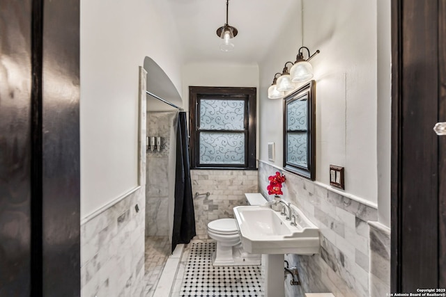 bathroom with sink, tile walls, tile patterned floors, and toilet