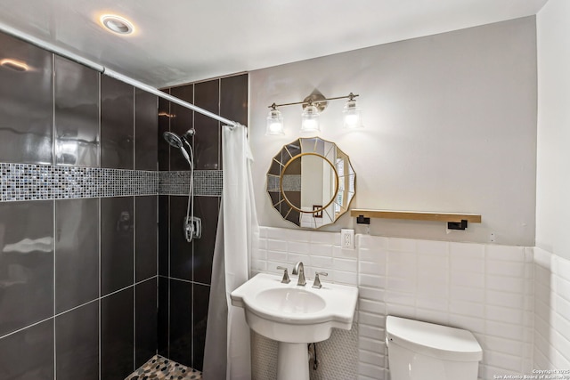 bathroom with toilet, curtained shower, sink, and tile walls