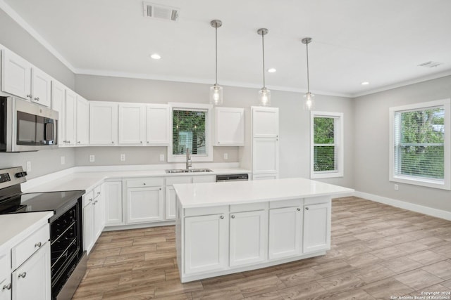 kitchen featuring sink, a center island, pendant lighting, stainless steel appliances, and white cabinets