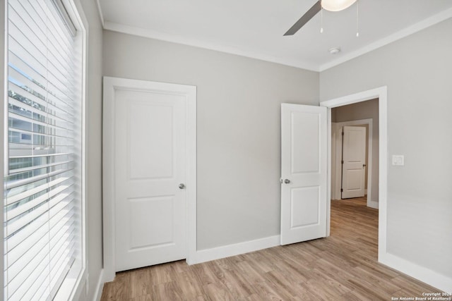 unfurnished bedroom with multiple windows, ornamental molding, and light hardwood / wood-style flooring