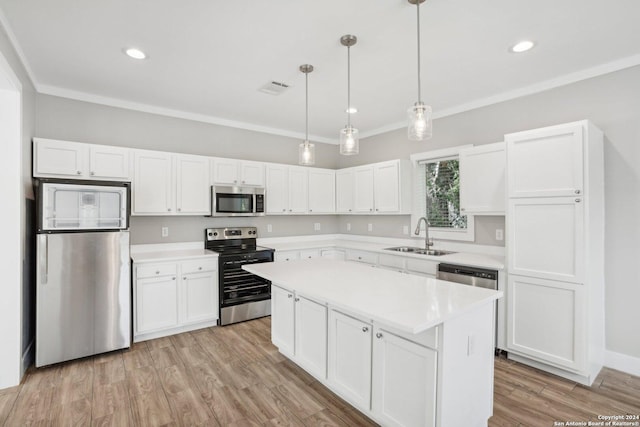 kitchen with sink, crown molding, decorative light fixtures, appliances with stainless steel finishes, and white cabinets