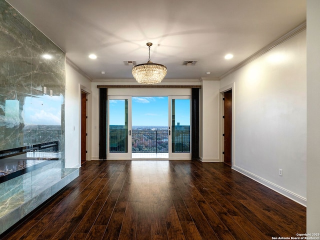 unfurnished room with dark wood-type flooring, ornamental molding, and a notable chandelier