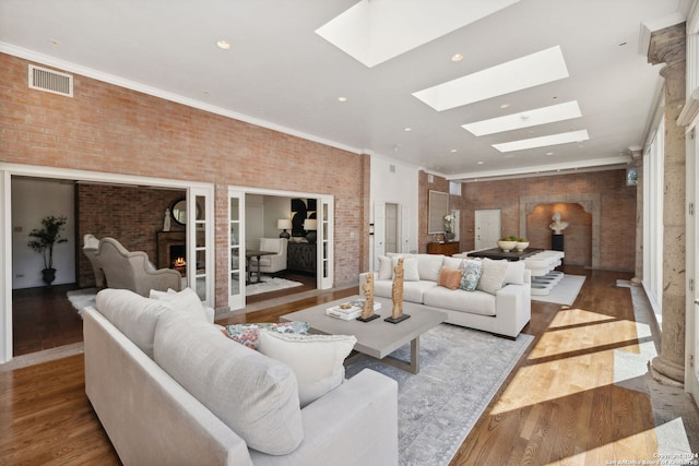 living room with crown molding, brick wall, a skylight, and light hardwood / wood-style floors