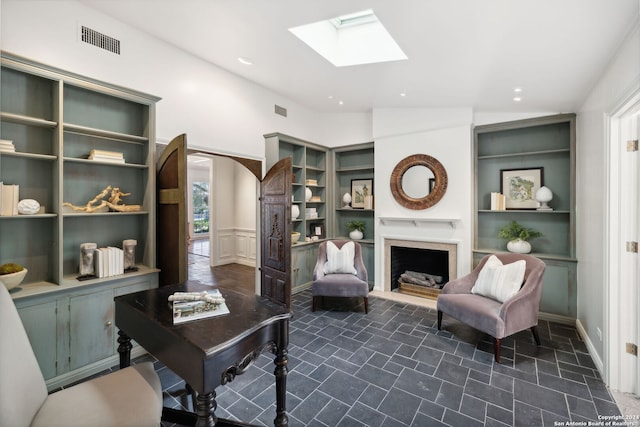 living area featuring vaulted ceiling with skylight and built in features