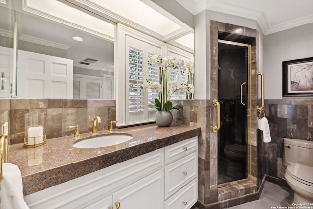 bathroom featuring tile walls, vanity, toilet, a shower with door, and crown molding