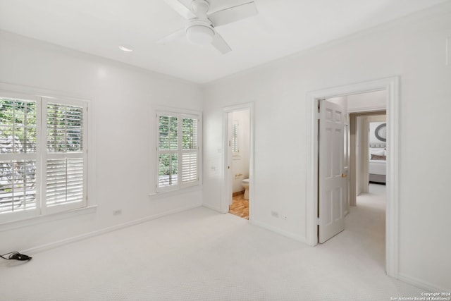 unfurnished bedroom featuring connected bathroom, light carpet, and ceiling fan