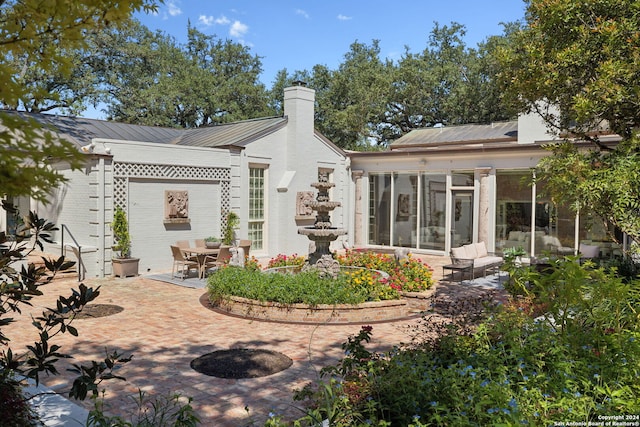 rear view of property with a sunroom and a patio