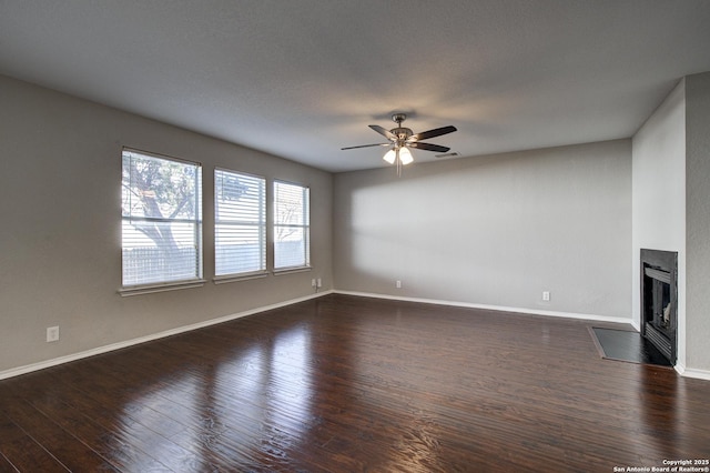 unfurnished living room featuring dark wood-type flooring and ceiling fan