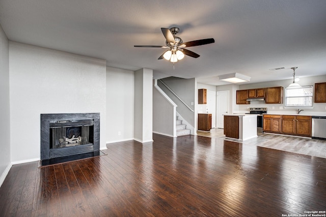 unfurnished living room with sink, hardwood / wood-style flooring, a high end fireplace, and ceiling fan