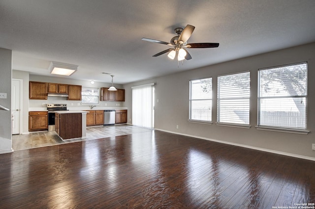 unfurnished living room with ceiling fan, wood-type flooring, sink, and a textured ceiling