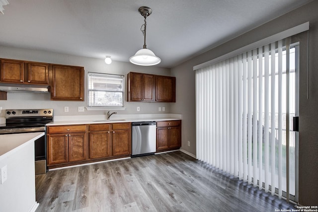 kitchen with pendant lighting, stainless steel appliances, light hardwood / wood-style floors, and sink