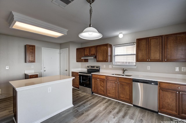 kitchen featuring sink, wood-type flooring, hanging light fixtures, a kitchen island, and stainless steel appliances