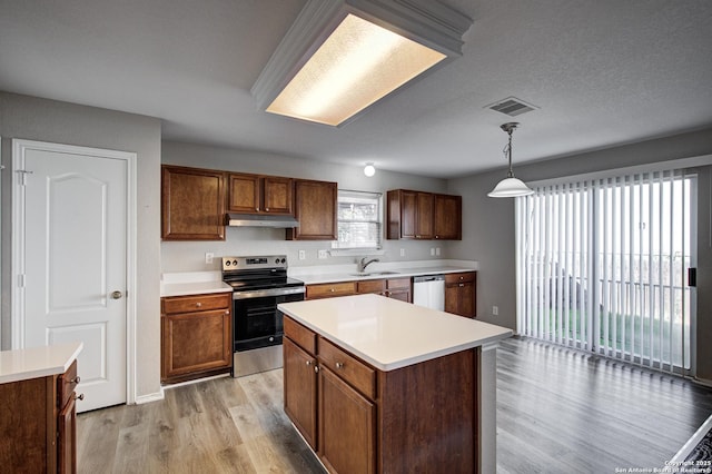 kitchen with sink, decorative light fixtures, a center island, light wood-type flooring, and appliances with stainless steel finishes