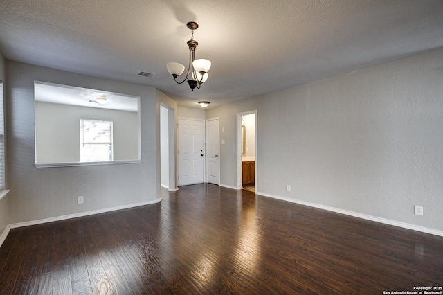 empty room with dark hardwood / wood-style flooring and a chandelier