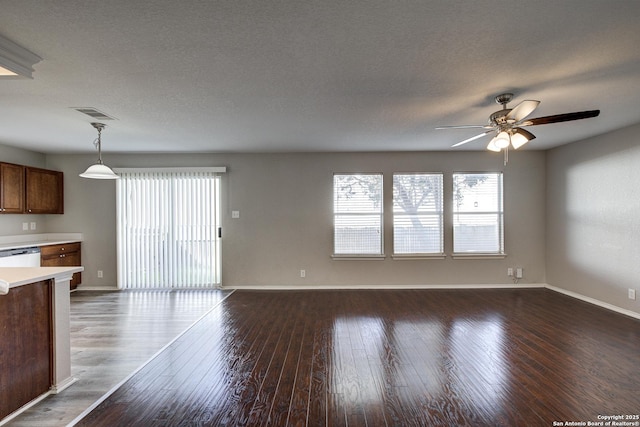 unfurnished living room featuring ceiling fan, dark hardwood / wood-style floors, and a textured ceiling