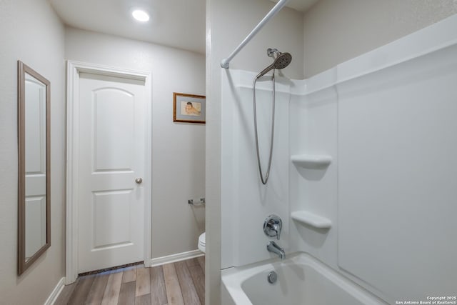 bathroom featuring hardwood / wood-style flooring, bathing tub / shower combination, and toilet