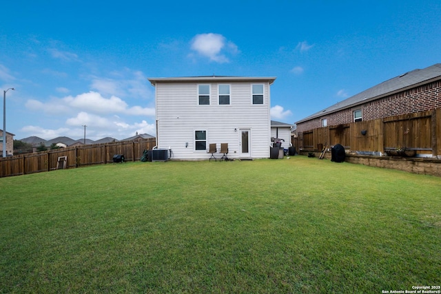 back of house with central AC unit and a lawn