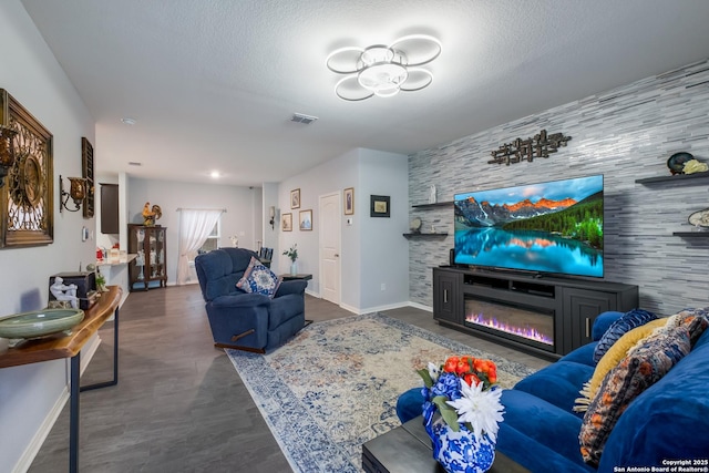 living area with an accent wall, baseboards, visible vents, and a textured ceiling