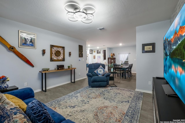 living area with baseboards, visible vents, and a textured ceiling