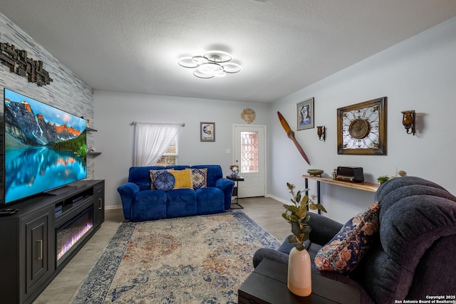 living room with light wood finished floors, a textured ceiling, and baseboards