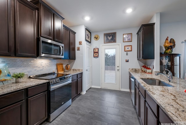 kitchen with sink, decorative backsplash, light stone counters, dark brown cabinetry, and stainless steel appliances