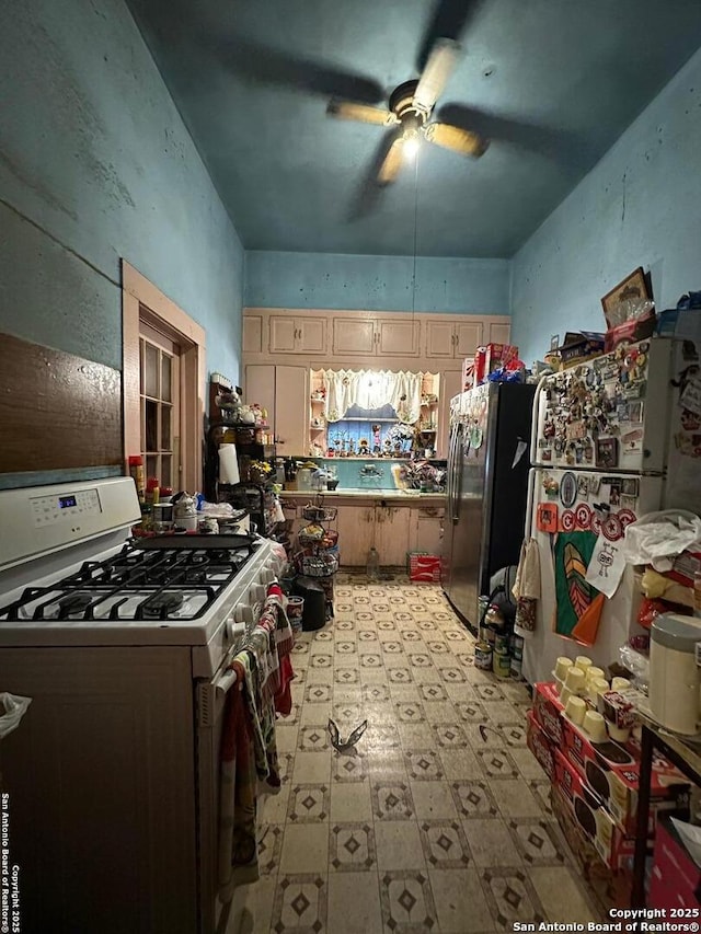 kitchen featuring ceiling fan, stainless steel fridge, and white range with gas stovetop