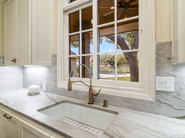 kitchen with ceiling fan, sink, backsplash, and light stone counters