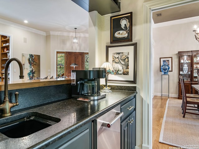 kitchen featuring sink, light hardwood / wood-style flooring, ornamental molding, pendant lighting, and dark stone counters