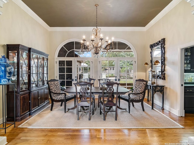 dining space featuring hardwood / wood-style flooring, crown molding, a notable chandelier, and french doors