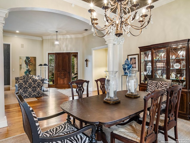 dining space with crown molding, light hardwood / wood-style floors, and decorative columns