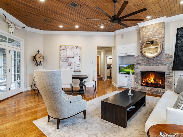 living room featuring crown molding, ceiling fan, a fireplace, wooden ceiling, and light wood-type flooring