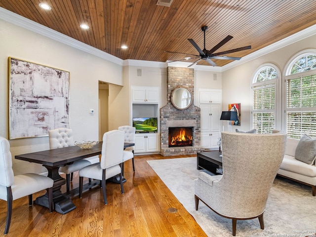 dining room with light hardwood / wood-style flooring, crown molding, a fireplace, and wooden ceiling