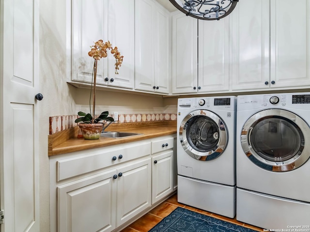 washroom with cabinets, washer and dryer, and sink