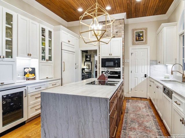 kitchen featuring wine cooler, sink, white cabinetry, decorative light fixtures, and black appliances