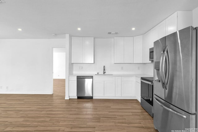 kitchen featuring light wood-type flooring, appliances with stainless steel finishes, sink, and white cabinets