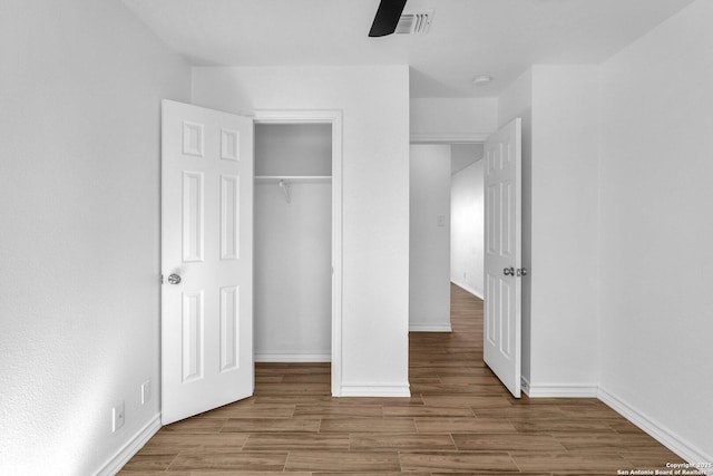 unfurnished bedroom with hardwood / wood-style floors, a closet, and ceiling fan