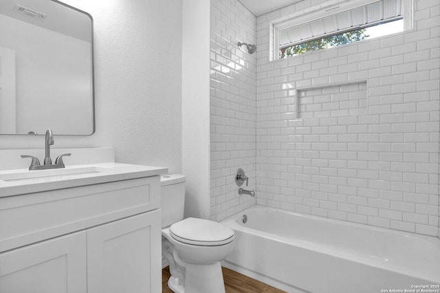 full bathroom featuring hardwood / wood-style flooring, vanity, toilet, and tiled shower / bath combo