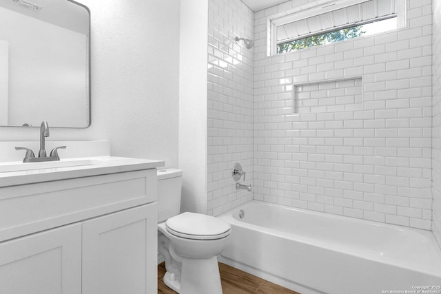 full bathroom with wood-type flooring, toilet, tiled shower / bath combo, and vanity