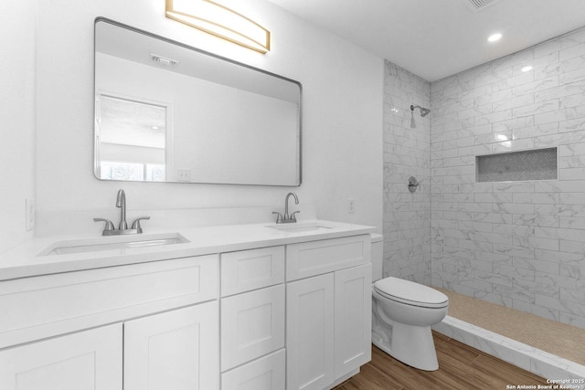 bathroom with vanity, hardwood / wood-style flooring, toilet, and tiled shower