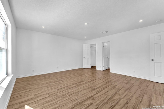 spare room featuring a textured ceiling and light hardwood / wood-style floors