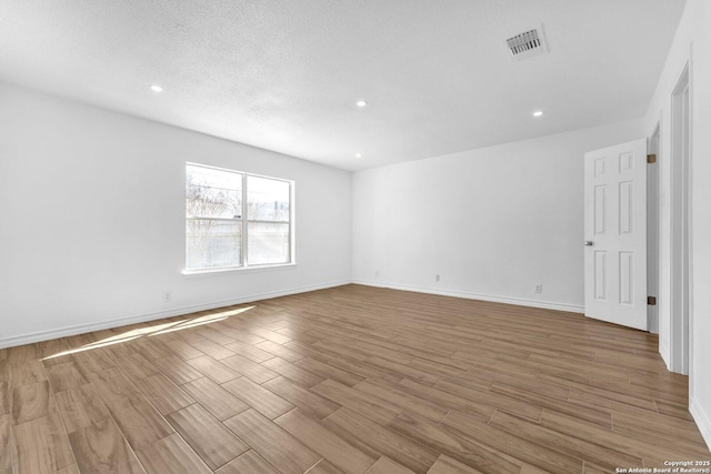 unfurnished room featuring a textured ceiling and light hardwood / wood-style flooring