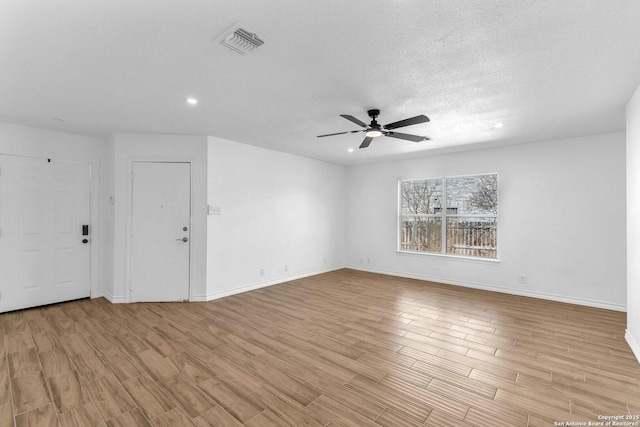 spare room with a textured ceiling, light hardwood / wood-style floors, and ceiling fan